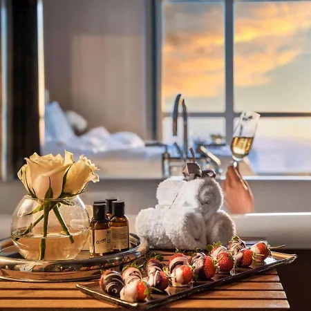 Fairmont Nile City Kairo Exterior foto The photo features a luxurious setting designed for relaxation. In the foreground, there's a wooden serving tray that holds several items: a small vase with fresh roses, a few bottles of spa products, neatly rolled white towels, and a plate of chocol